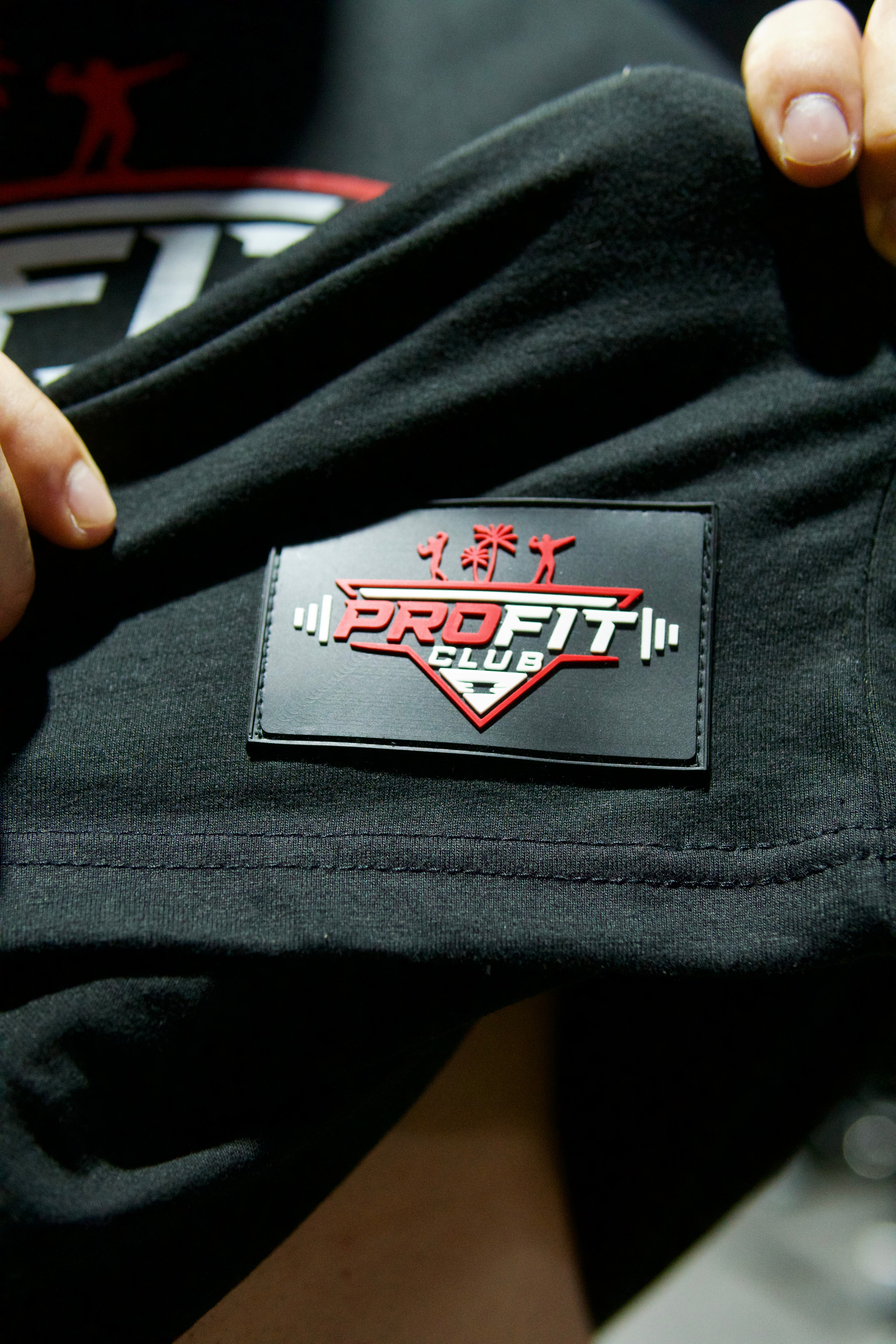 Hochwertiger ProFit Club Logo-Patch aus Gummi als Detail auf schwarzer Gymwear.