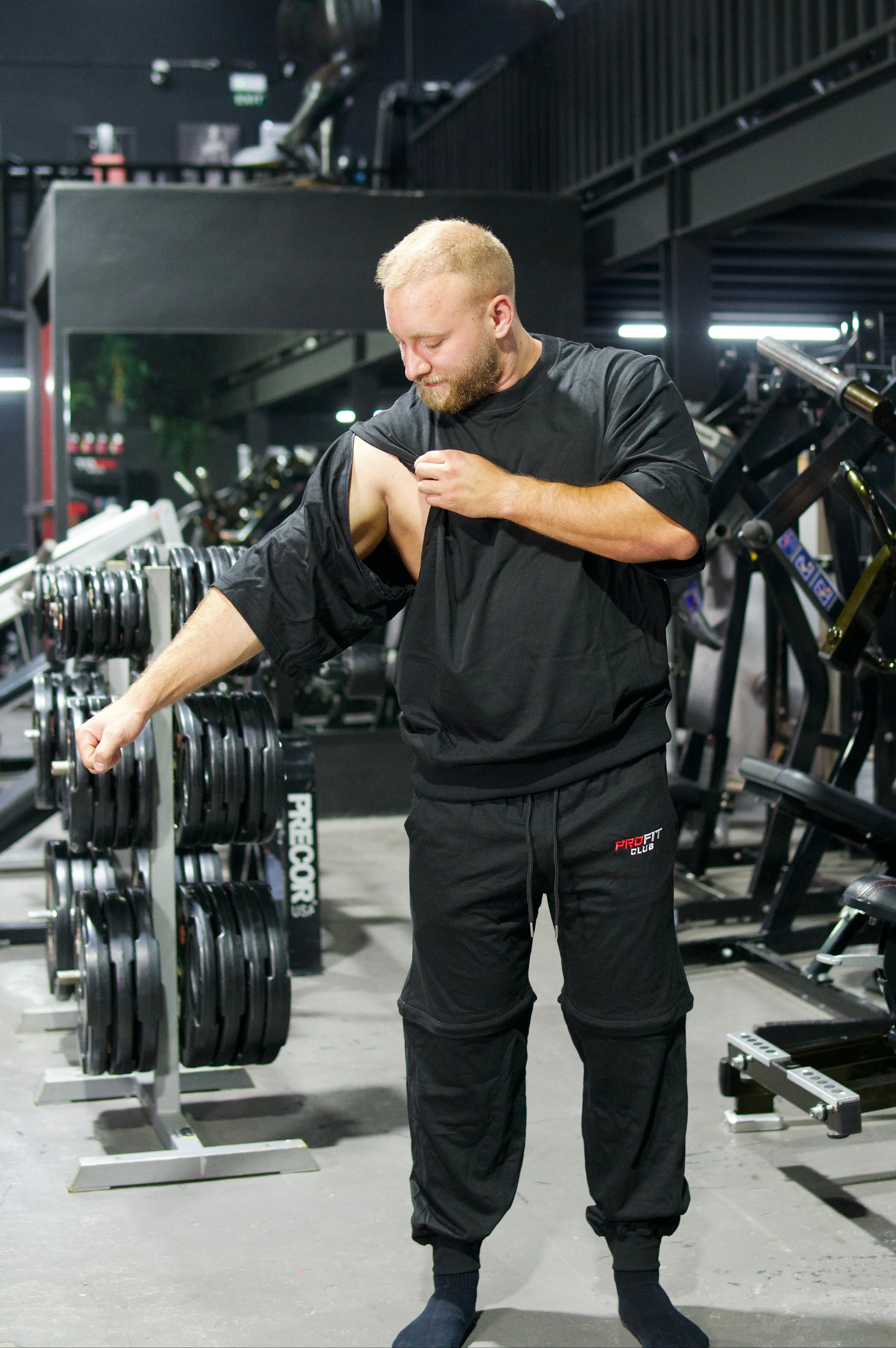 Athlet trägt ein schwarzes Zip-off-T-Shirt mit abnehmbaren Ärmeln und eine schwarze Zip-off-Hose im modernen Oversize-Look.