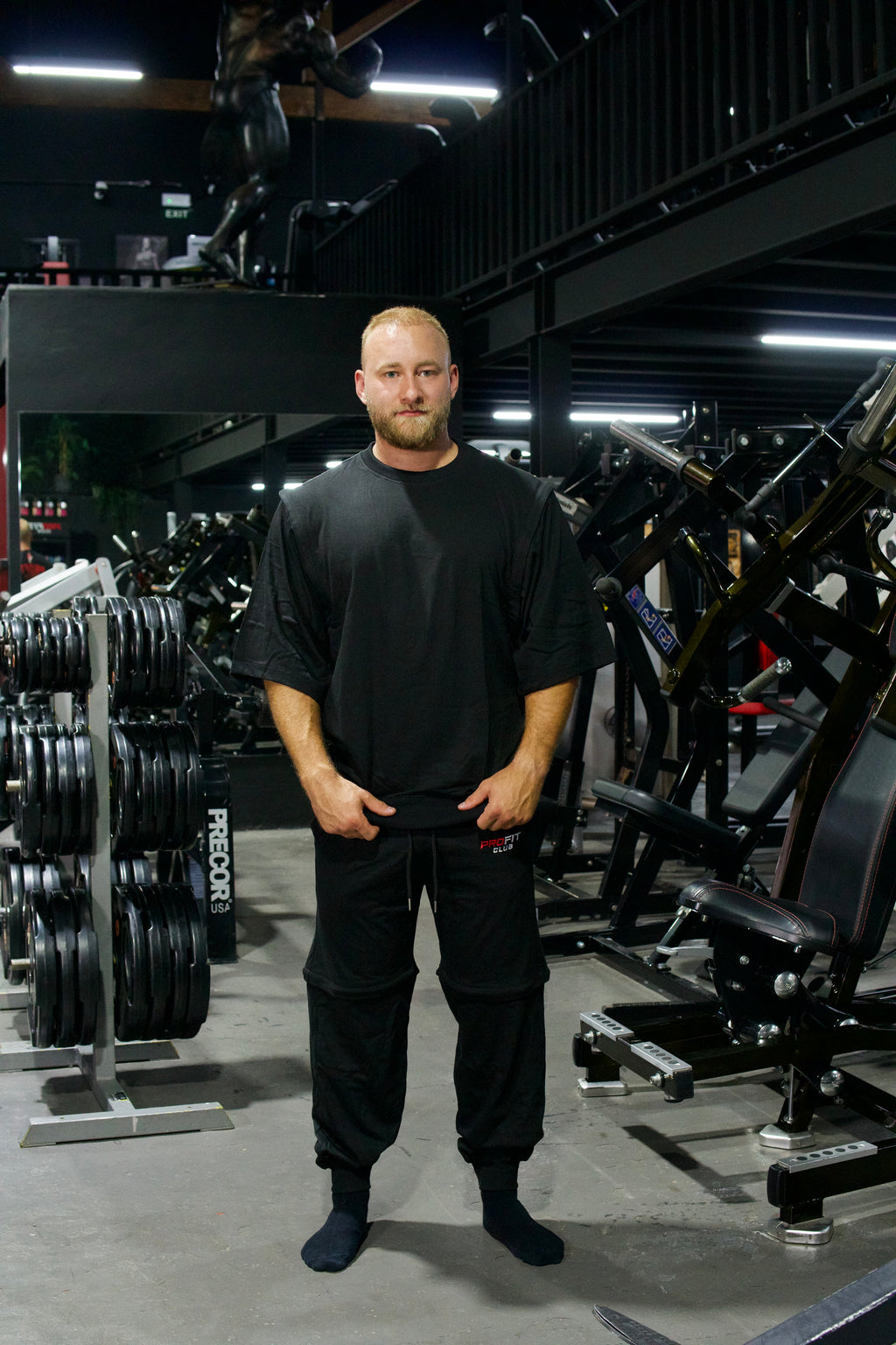 Athlet trägt ein schwarzes Zip-off-T-Shirt mit abnehmbaren Ärmeln und eine schwarze Zip-off-Hose im modernen Oversize-Look.